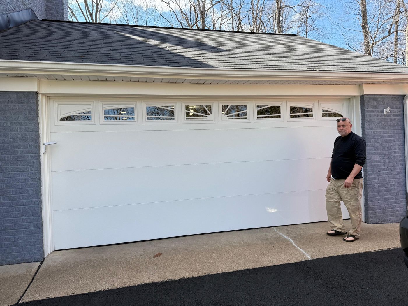 White garage door with a row of sunburst windows and a person standing beside it