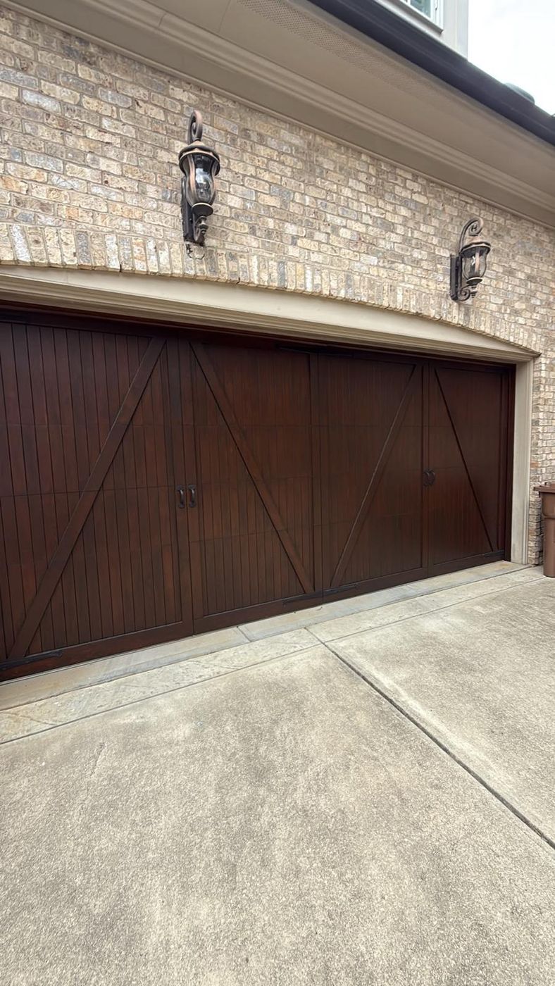 Dark wood carriage-style double garage doors on a brick house